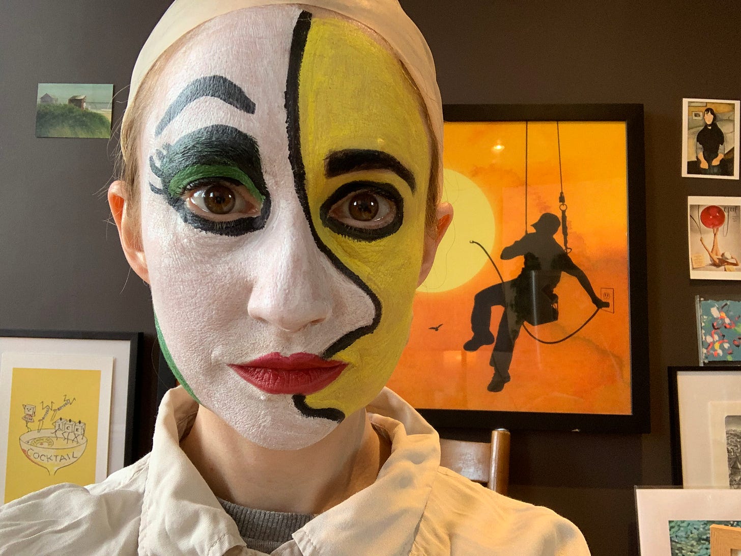 photo of Susan with face paint to look like a painting and surrounded by art on the wall behind her 