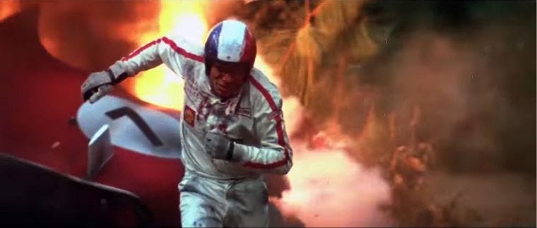 Movie still from Le Mans. A racecar driver runs out of a flaming racecar.