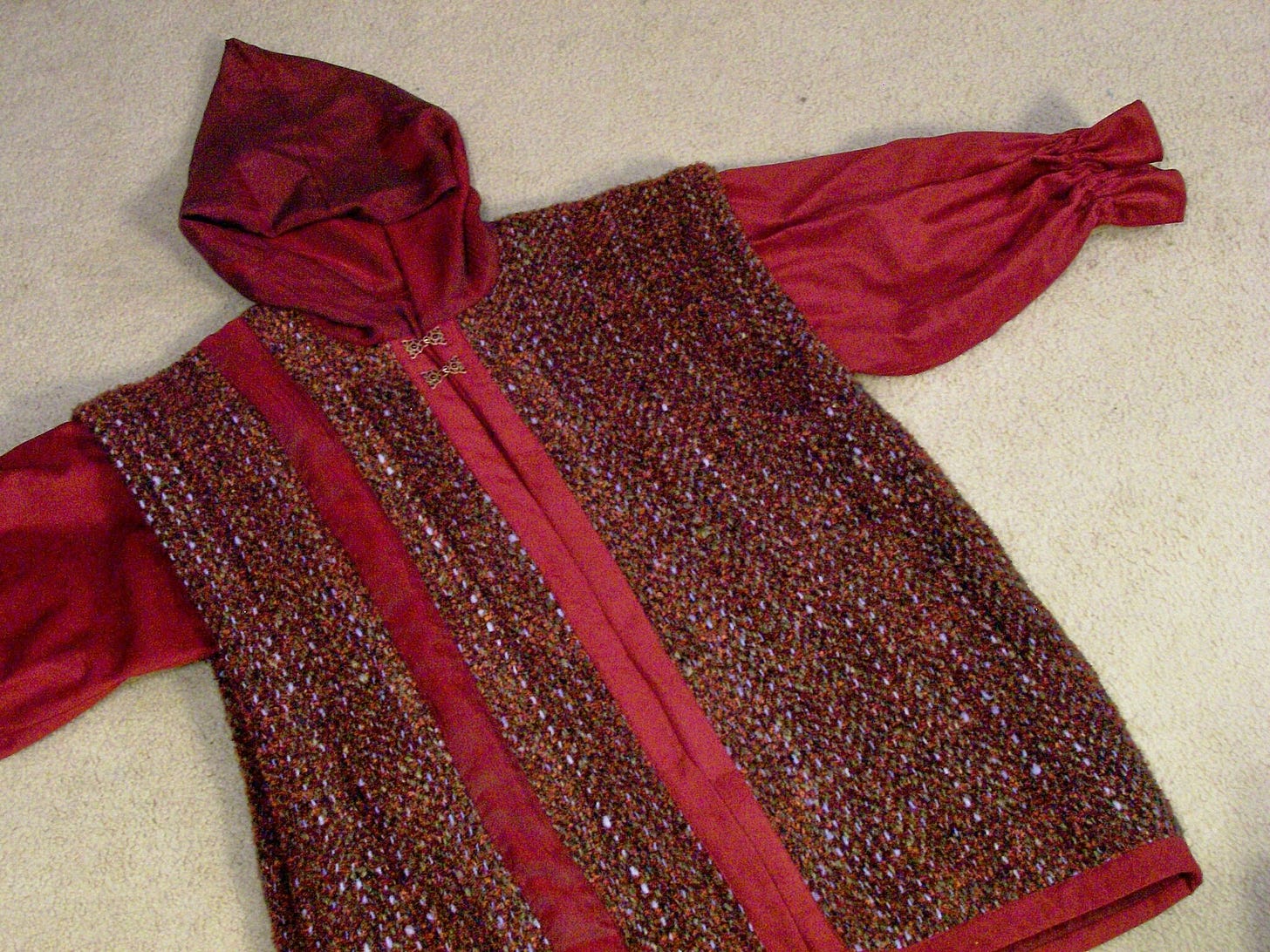 A jacket in shades of burgundy and grayish brown. The body is handwoven wool; the sleeves, hood, and trim are suedecloth.