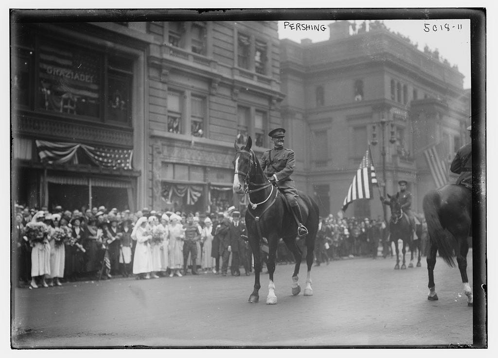 General Pershing on horseback in uniform leading a World War I veteran's parade in New York. Black and white photo in uniform. Streets are crowded with observers