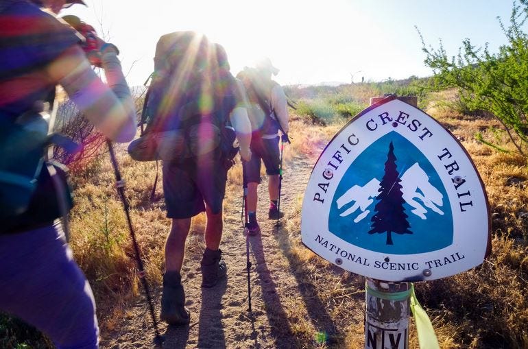 Senderistas caminando junto a una señal del Pacific Crest Trail