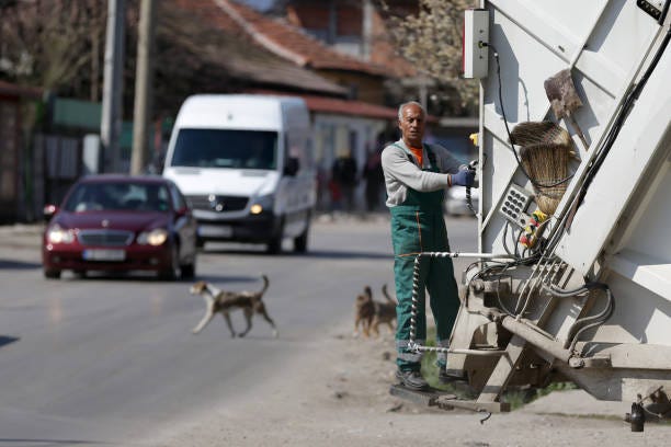 Garbage collector garbage truck Sofia, Bulgaria - 11 April, 2020: Garbage truck worker travels on the vehicle during his work shift, dogs on garbage trucks stock pictures, royalty-free photos & images