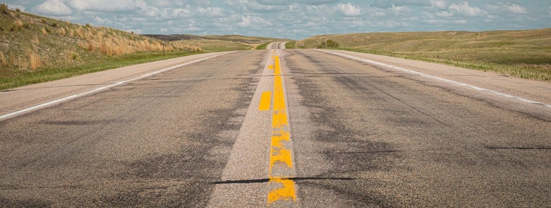 gray concrete road under white clouds and blue sky during daytime