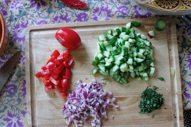 chopped tomatoes, cucumbers, mint, red onion on a chopping board