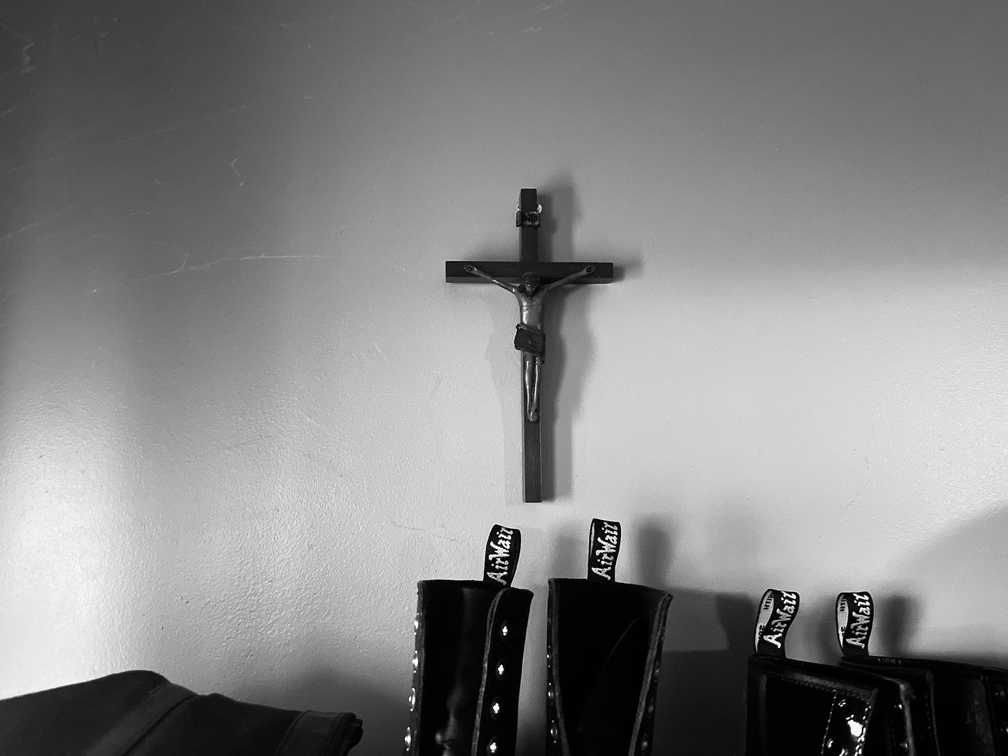 A crucifix hanging above the bookcase I use for shoes, located at the entrance to my house.  (I really should get to dusting…)  