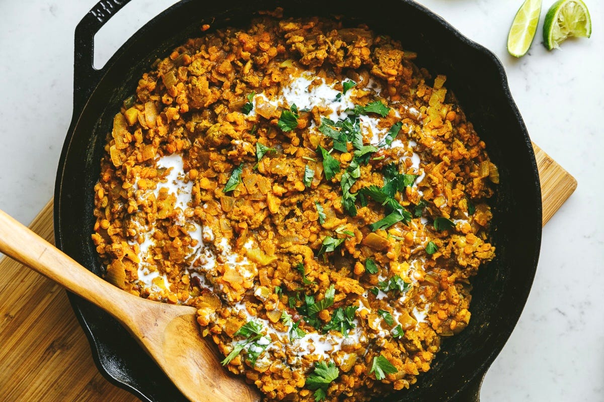 Low-carb dahl in a skillet with cilantro and coconut milk on top.