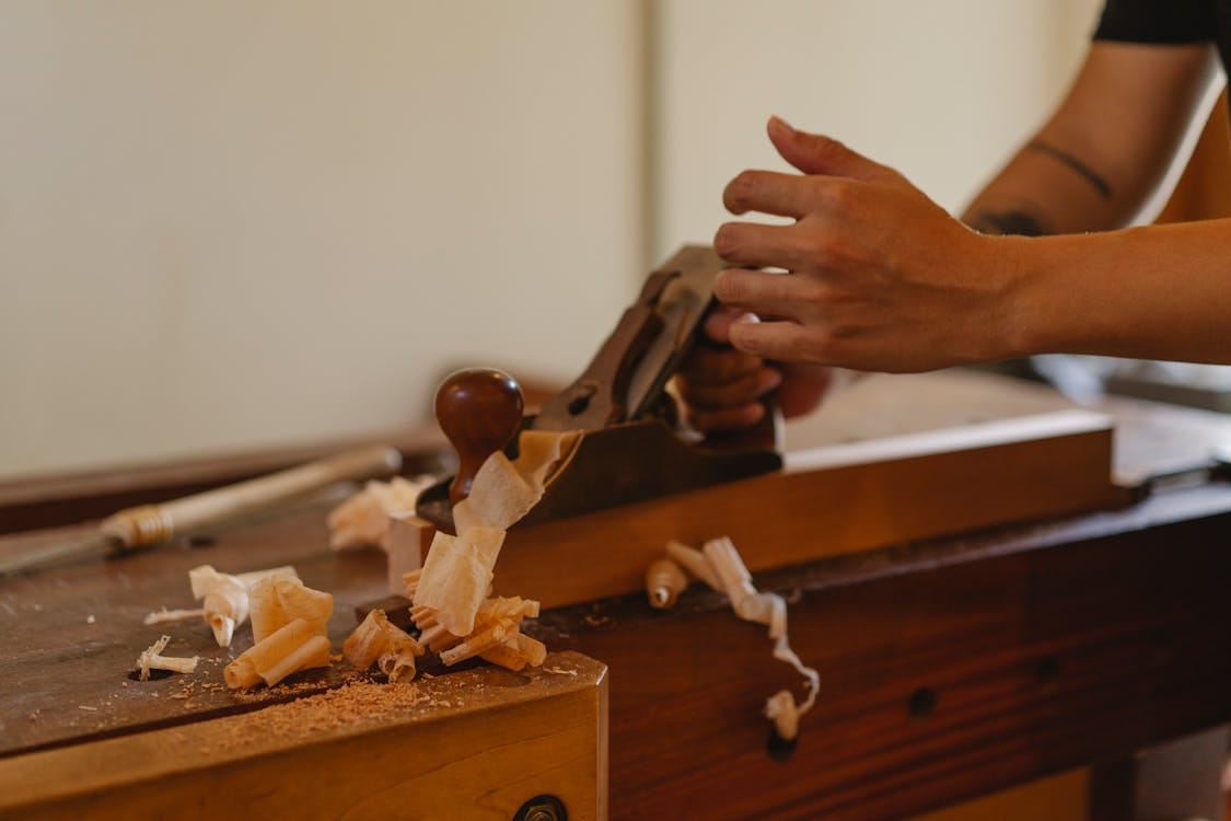 Free Crop joiner shaping hardwood plank with jack plane working at table in modern workshop Stock Photo