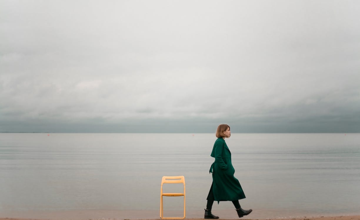 Free A solitary woman walks by the ocean, capturing calm and introspective solitude. Stock Photo