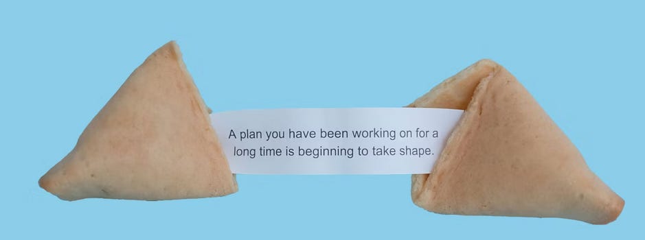 Picture of a fortune cookie broken in half, with the printed fortune saying "A plan you have been working on for a long time is beginning to take shape"