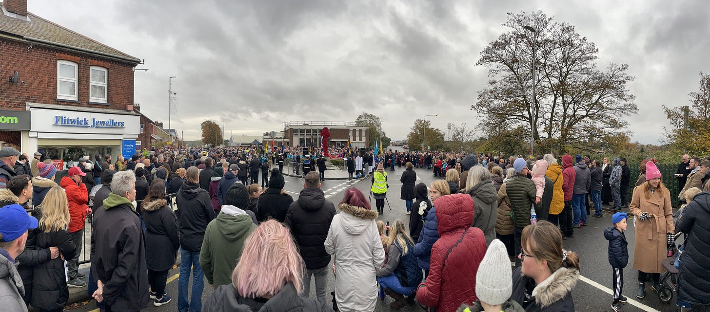 a crowd gathers around a war memorial