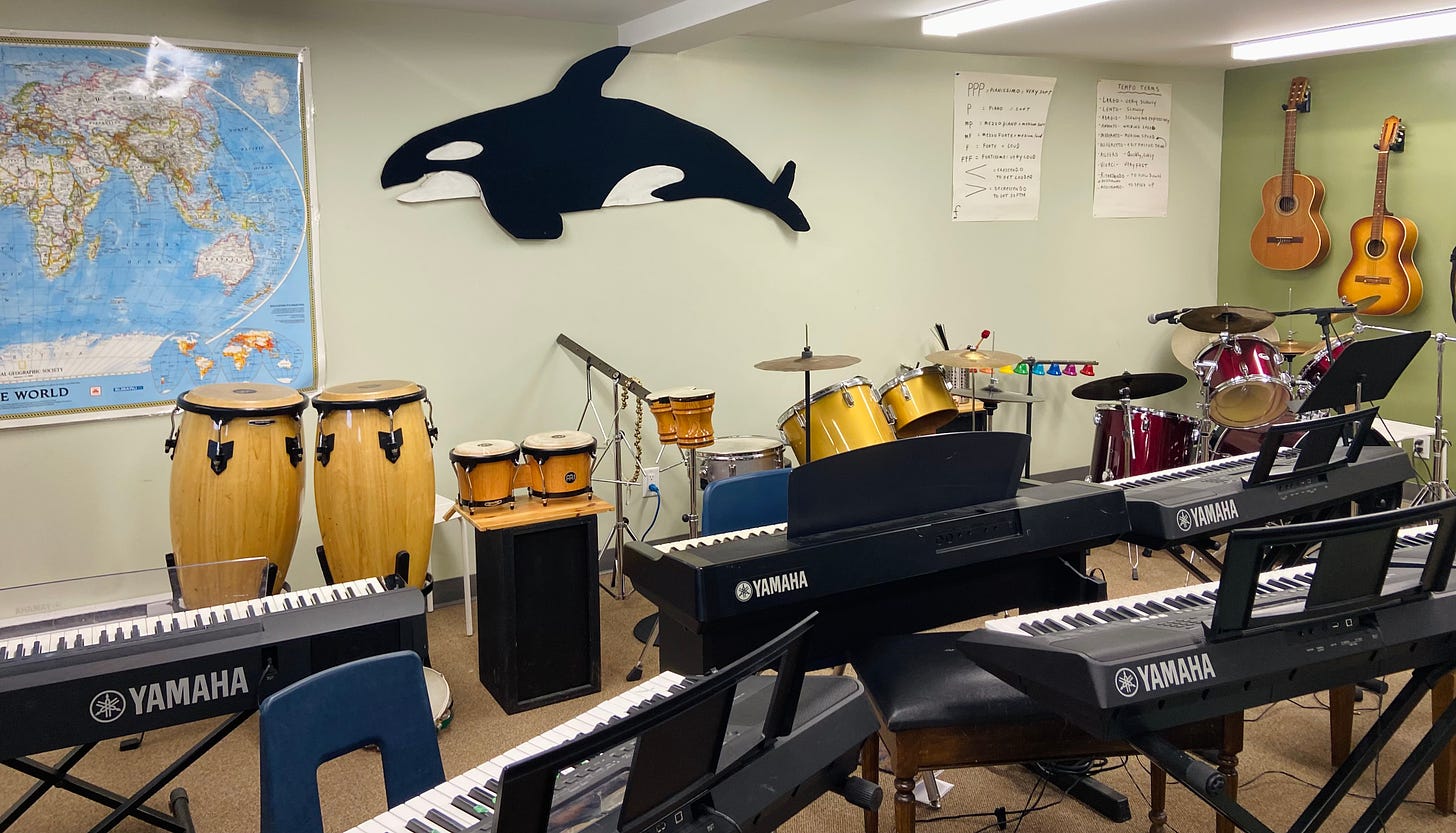 A music classroom with electric keyboards, guitars, and percussion instruments