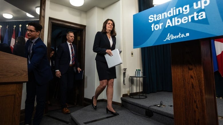 A woman in a dark suit walks to a podium.