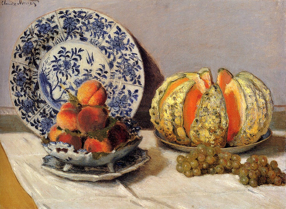 A still life of fruit on a white tablecloth with a light gray background. On the left side, a blue and white plate leans against the wall; in front of it, there’s a pyramid of peaches in a shallow dish with undulating edges, set atop another dish. To the right, the focal point (in that it’s the most vibrant, both in its dynamic detailing and how it catches the light) is a cantaloupe split into eight pieces and arranged on a plate like the petals of a flower, with two bunches of golden grapes on the table in front of it.