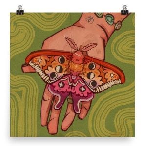 a print of a hand holding out a moth in lesbian flag colors