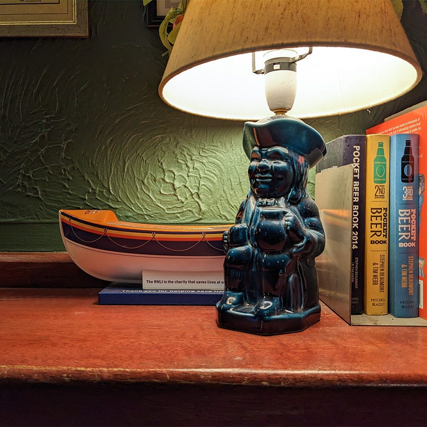 A lamp made from a toby jug on the shelf in a pub.