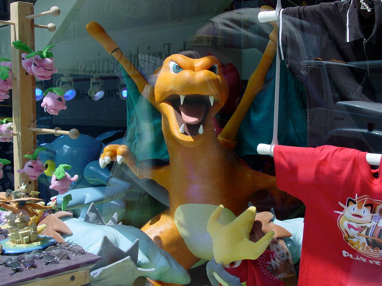 A close-up photo taken from outside the store of the Charizard statue from the window display