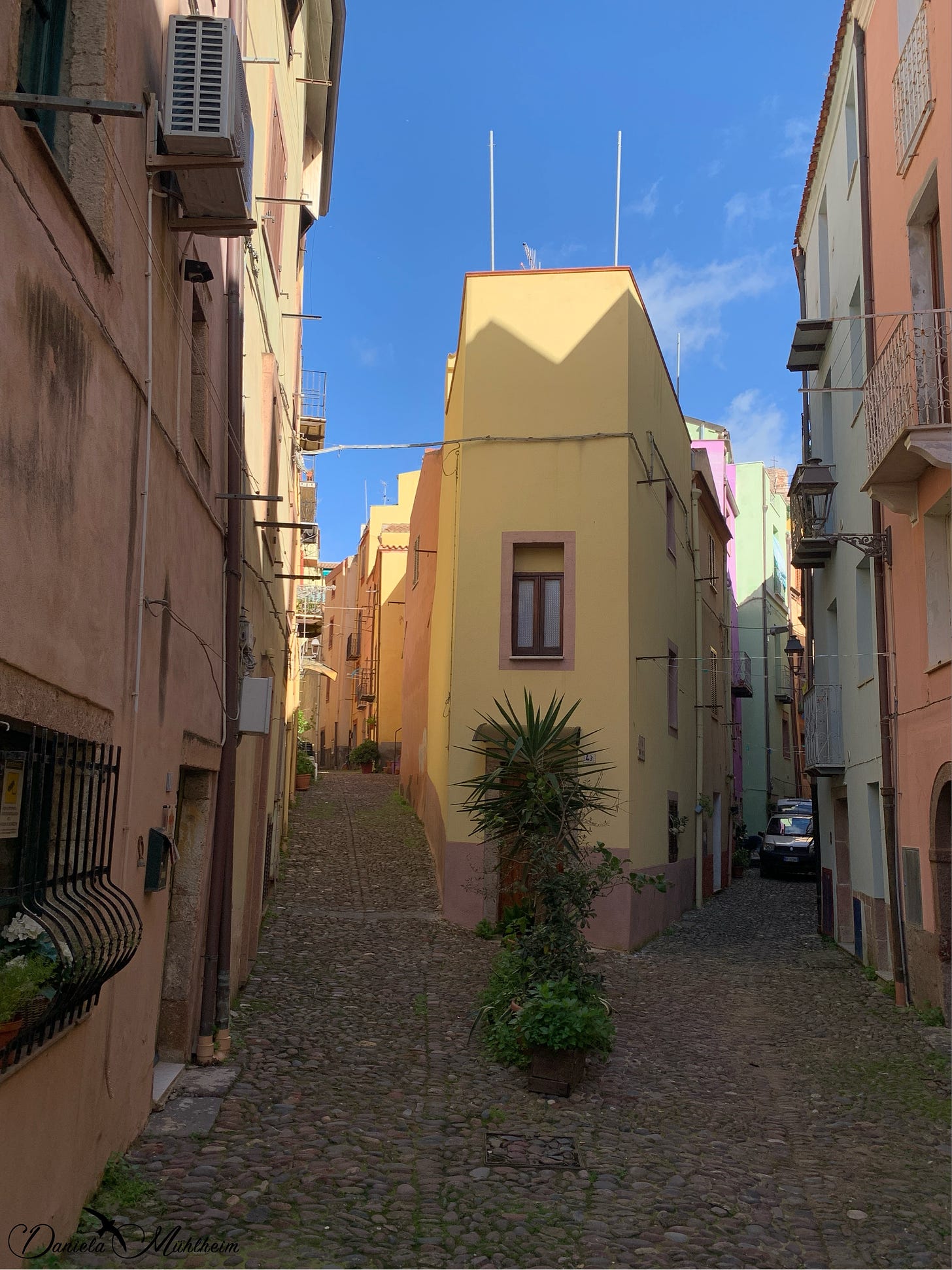 narrow and colourful streets in an italian town, a car can be seen in one of the two streets