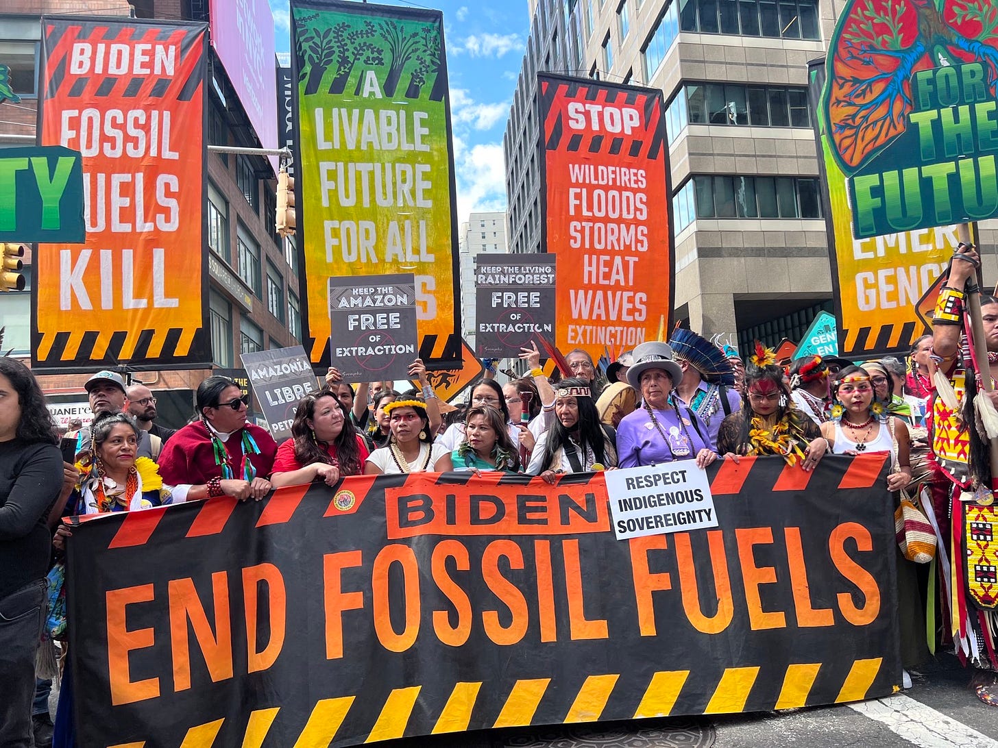 Indigenous leaders stand at the front of the March to End Fossil Fuels holding signs that say, "No Fossil Fuels" and "Respect Indigenous Sovereignty"