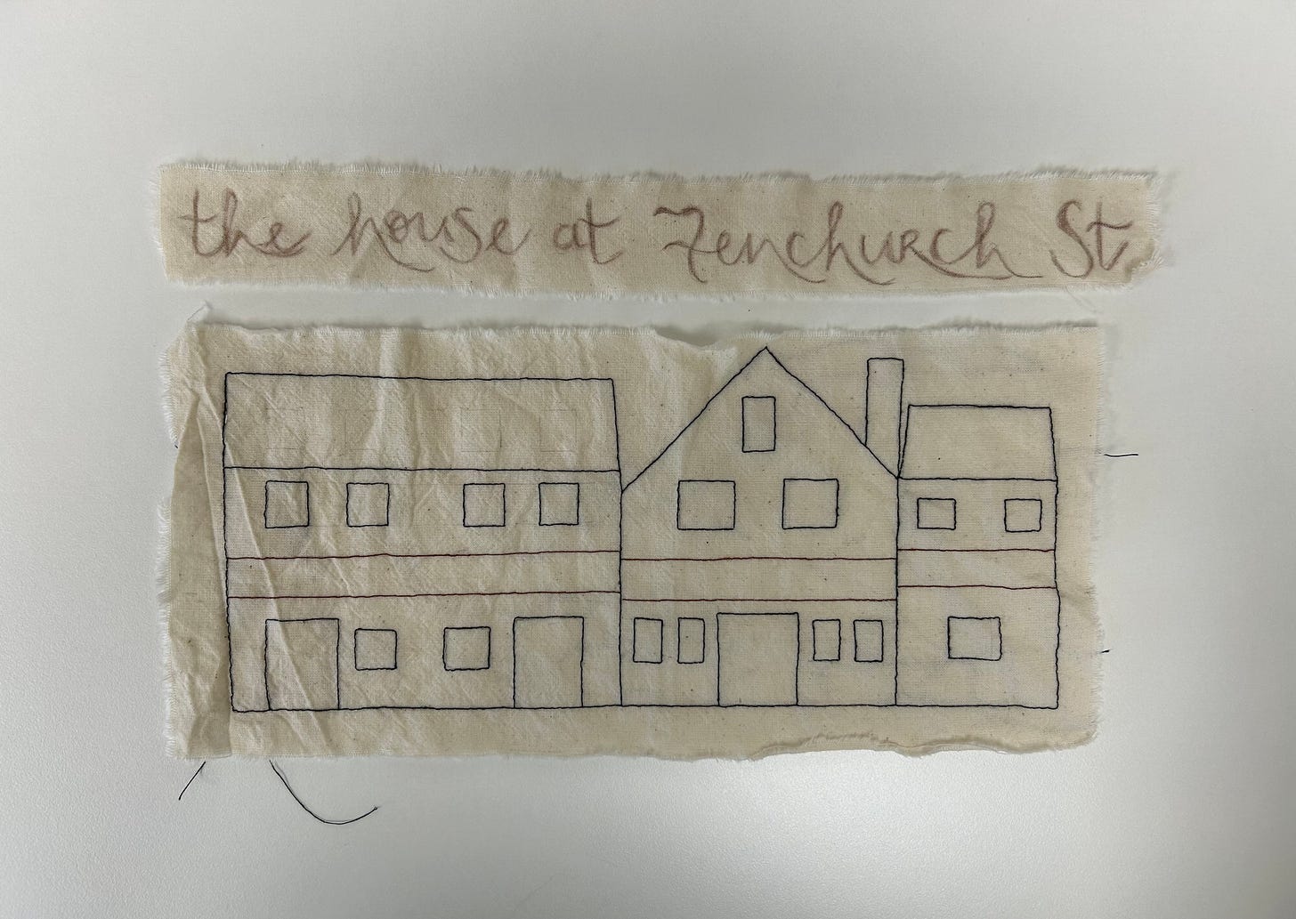 Two pieces of cream coloured fabric, one reading “the house at Fenchurch St”; the other is a representation of a building in three parts stitched in outline