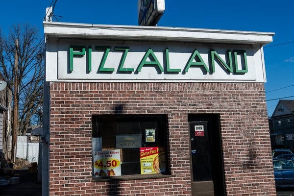 A sunnier shot of the "Pizzaland" building shows advertising in the window and an "open" sign on the door.