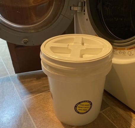 white bucket next to open washing machine