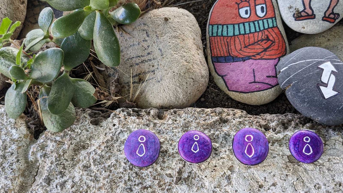 Image of a cacti closeup and some painted rocks, with 4 Team O'clock logo rocks in the front