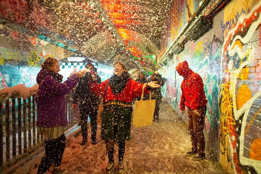 A woman walking through fake snowfall in the Leake Street graffitti tunnels