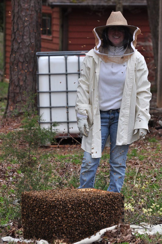 beekeeper standing next to a hive box covered in honey bees