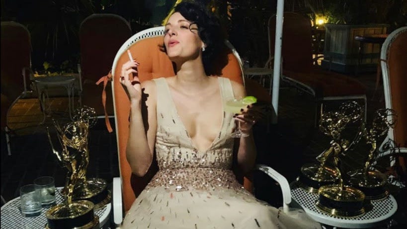 Phoebe Waller-Bridge is smoking a cigarette, drinking a cocktail, and reveling in a whole table full of little statue awards.