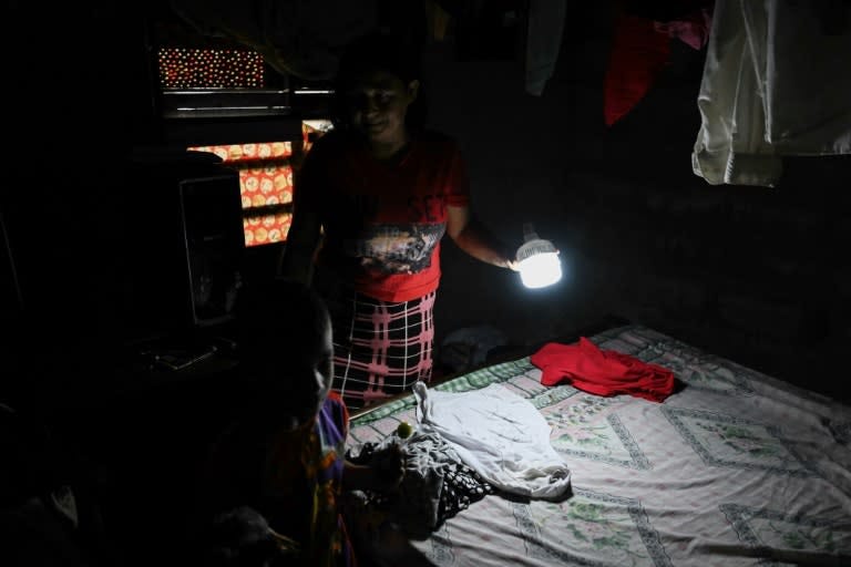 Una residente del barrio Nicolás Maduro de Barinas, en Venezuela, muestra un cuarto con una linterna durante un apagón el 3 de julio de 2024 (Juan Barreto)