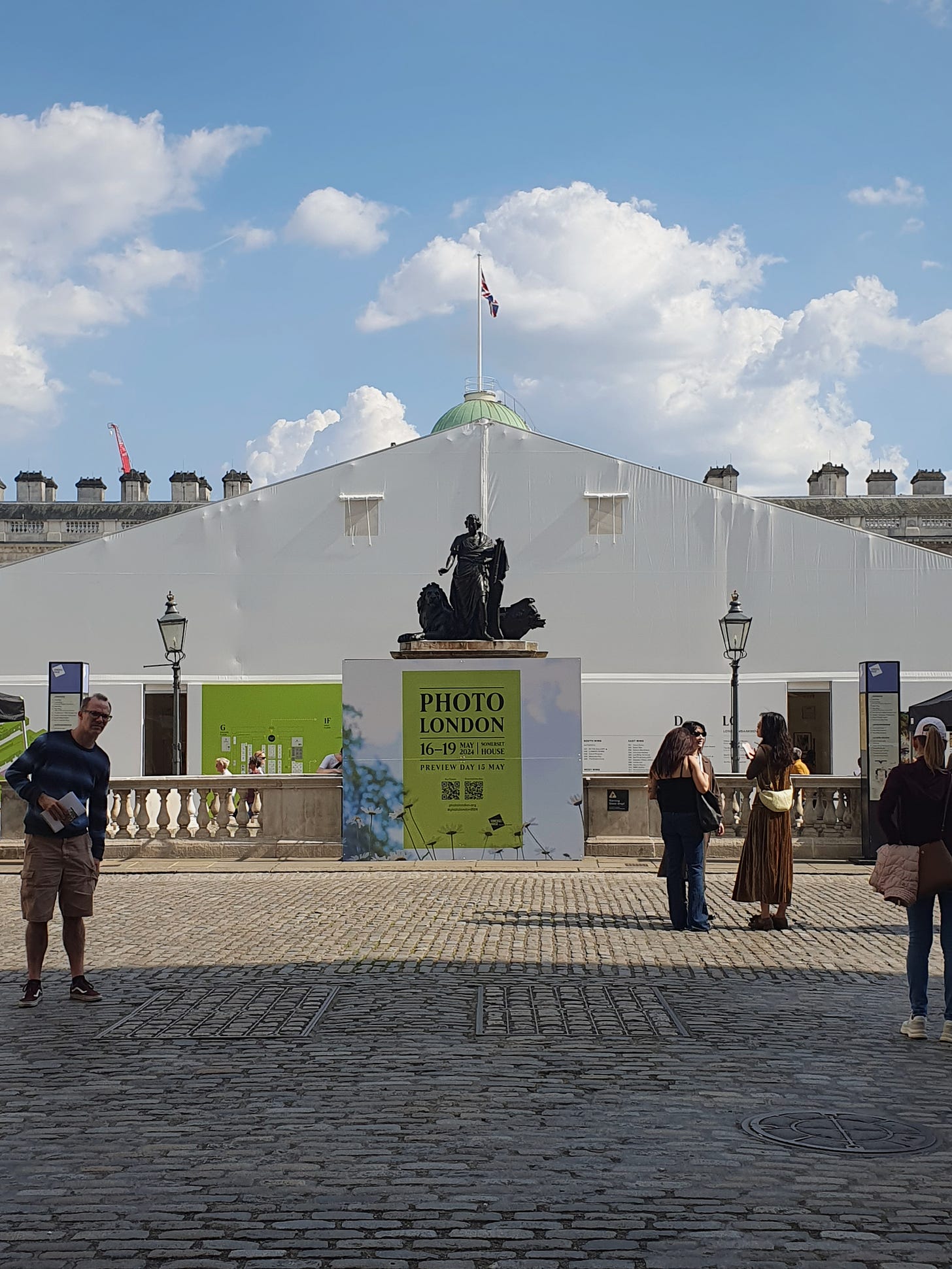 Photo of a white pavillion set up in front of Somerset House with people walking past in the foreground.