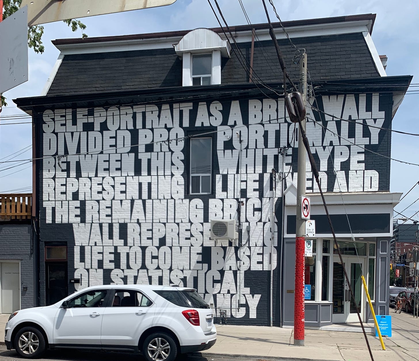 A building painted dark grey with white block text that covers an entire wall.