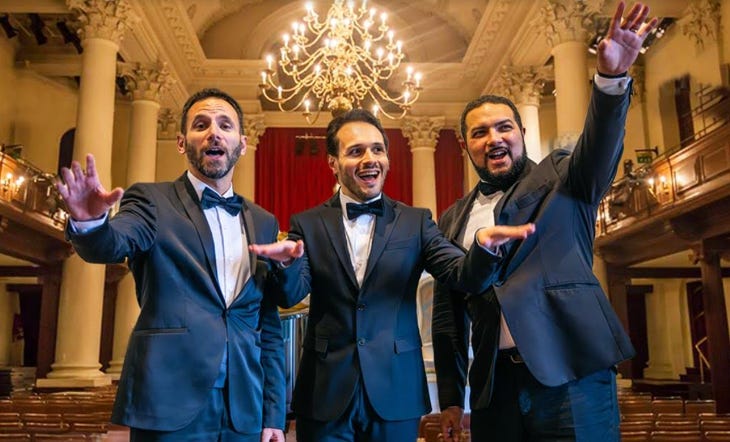 Three singers in suits and bow ties in a theatre