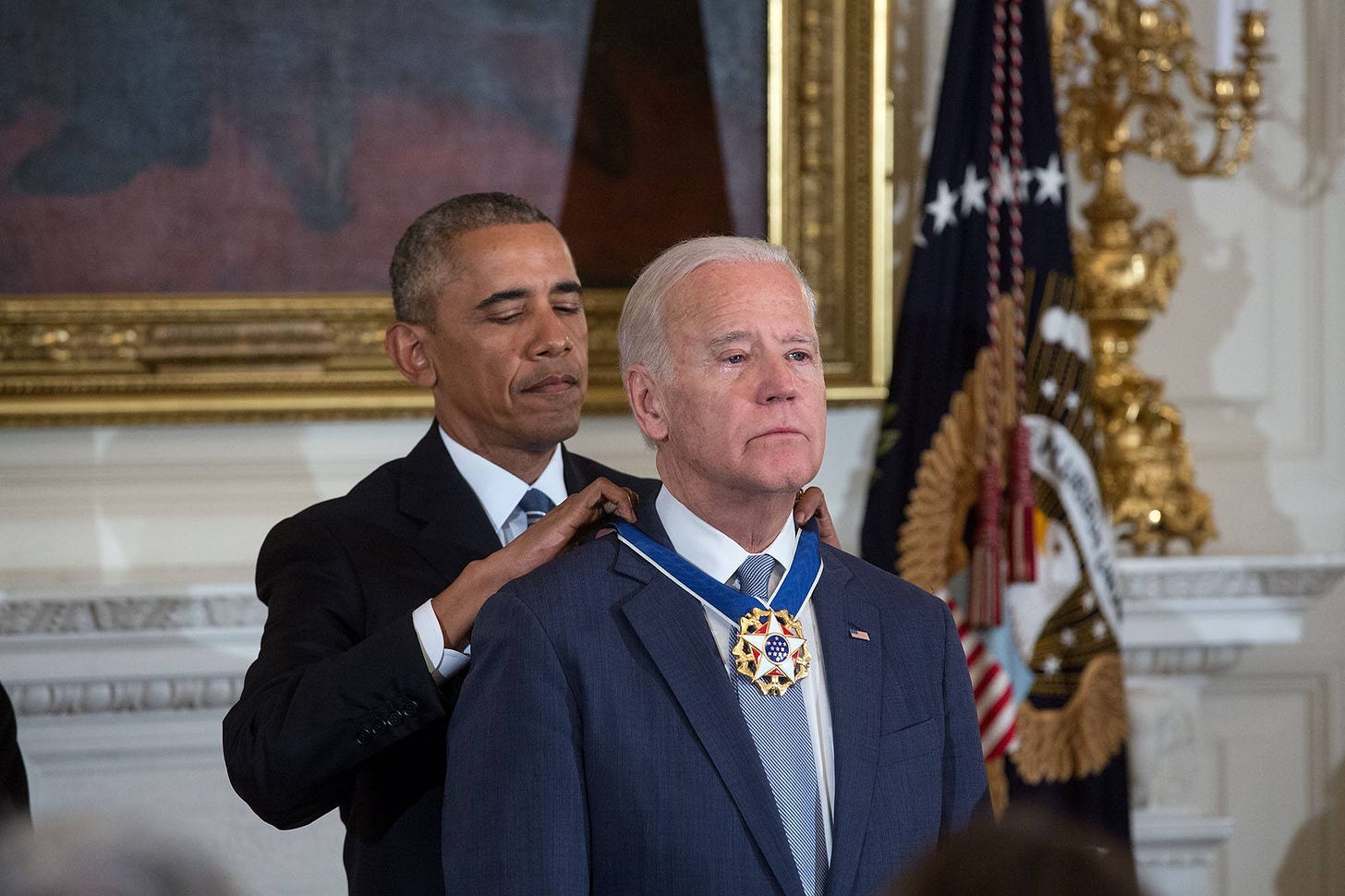 Photo of Obama placing a medal on Biden, who looks emotional but solemn