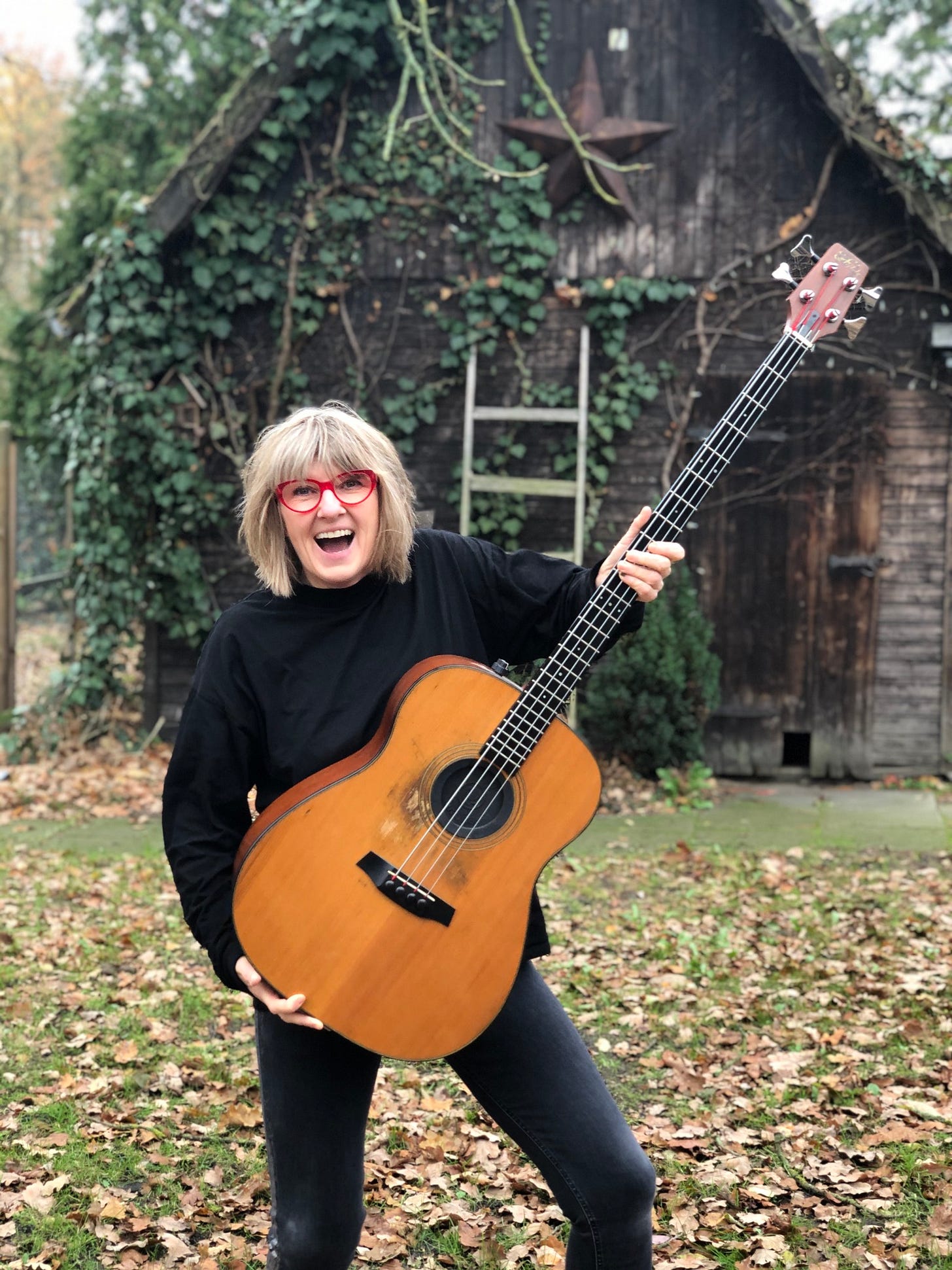 Woman with glasses holding a bass guitar outside