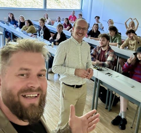 Jakub s Martinem se vyfotili před třídou studentů, kteří se do záběru pitvoří. 