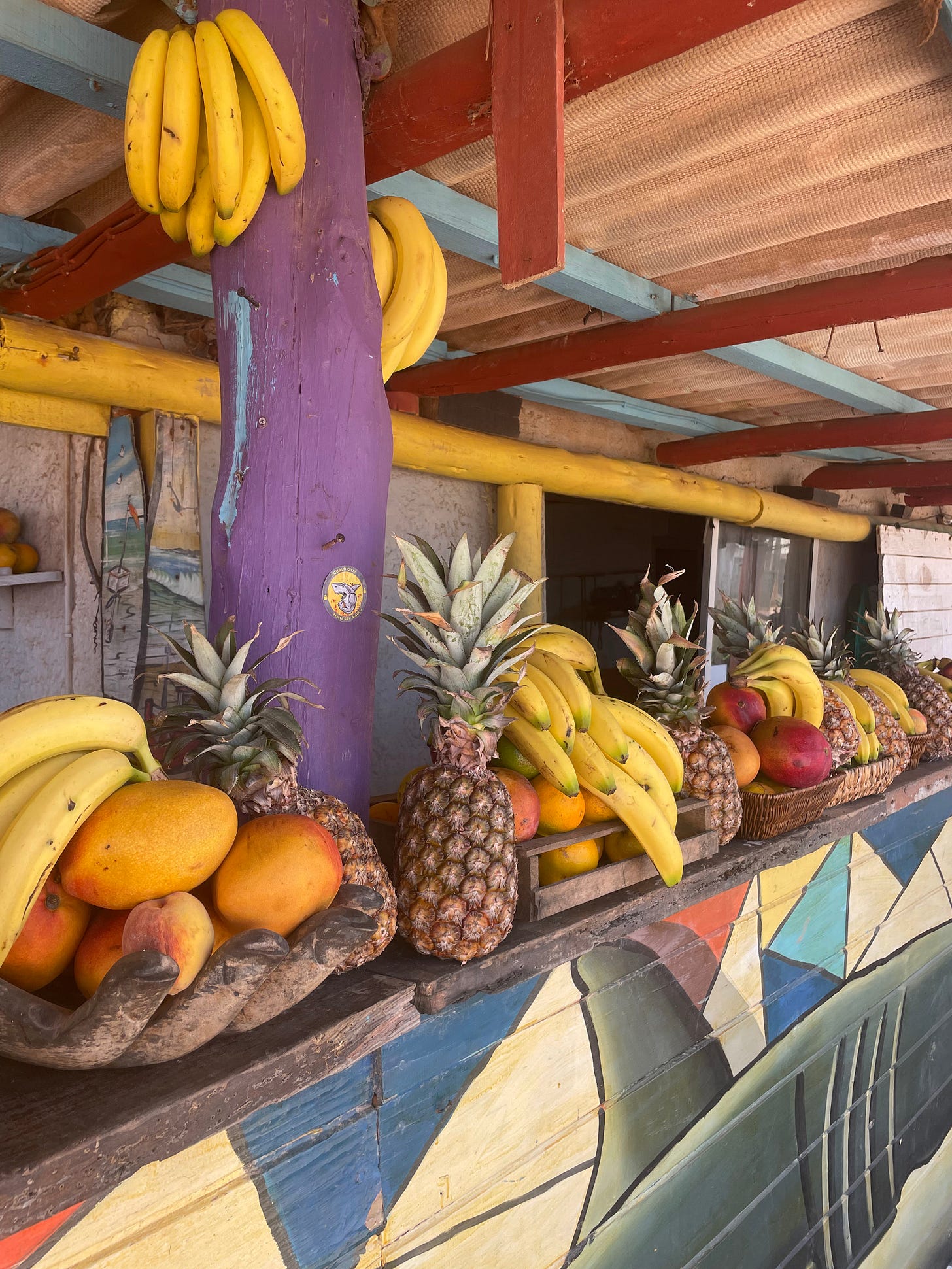 a juice store with fresh pineapples, bananas, and mangos decorating the front it