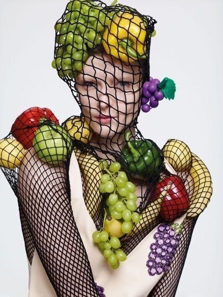 This may contain: a woman with fruit on her body and netted headdress