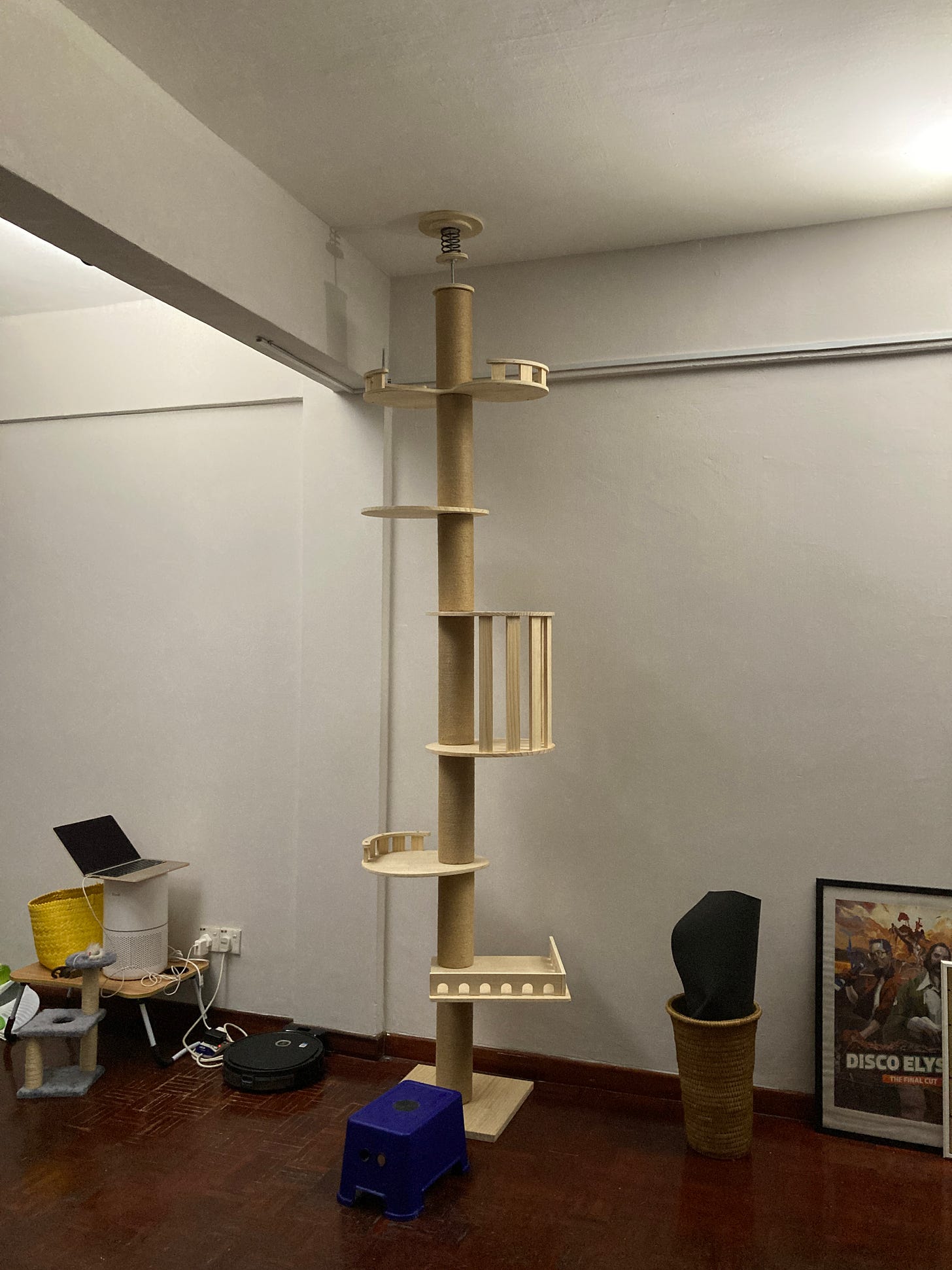 A five level cat tree sits in the corner of a room, lit brightly on either side