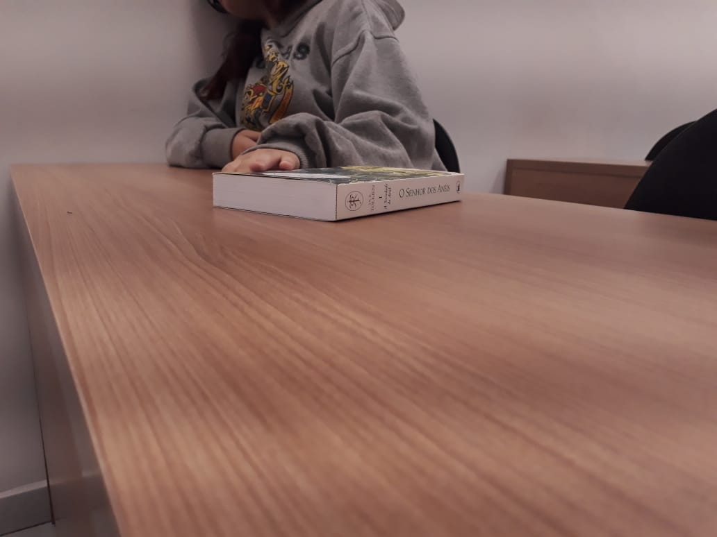 Jovem com livro fechado sobre a mesa.