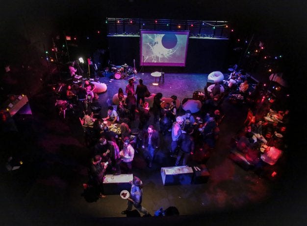 Birds eye image of 14th st Y black box theater filled with musicians and audience members with low moody lighting