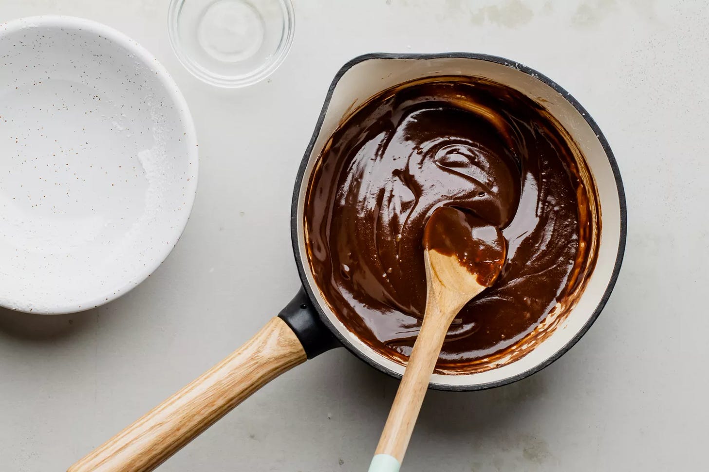 Sugar being stirred into smooth chocolate mixture with a wooden spoon