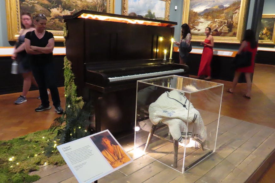 A replica of Taylor Swift's folklore piano and her cardigan on display in the V&A