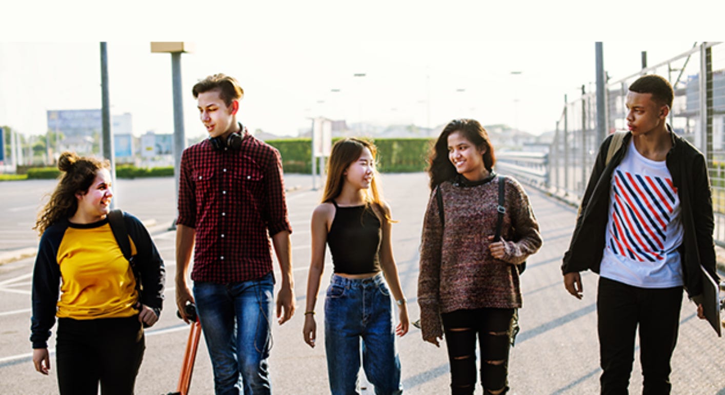 A diverse group of 5 teens walking on a city street