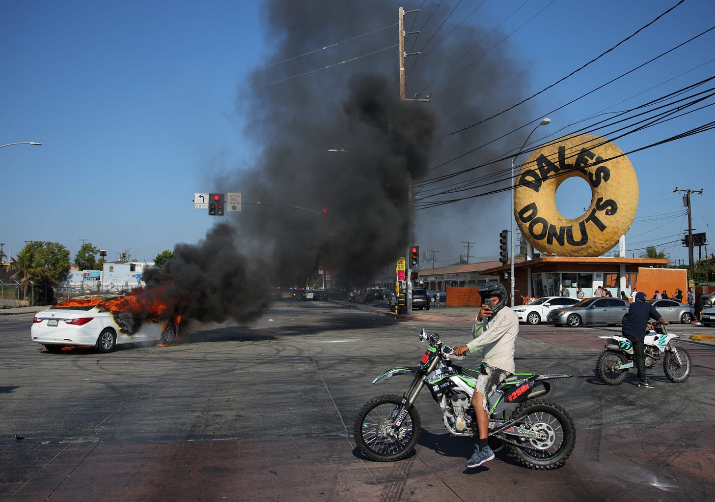 People ride motorbikes next to a car burning in flames during a standoff between police and protesters following multiple detentions by Immigration and Customs Enforcement (ICE), in the Los Angeles County city of Paramount, California, U.S., June 7, 2025 People ride motorbikes next to a car burning in flames during a standoff between police and protesters following multiple detentions by Immigration and Customs Enforcement (ICE), in the Los Angeles County city of Paramount, California, U.S., June 7, 2025