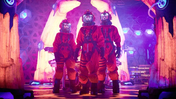 This image shows, from left to right, Yasmin "Yaz" Khan (played by Mandip Gill), the Thirteenth Doctor (played by Jodie Whittaker), and Dan Lewis (played by John Bishop) standing inside the TARDIS and wearing orange spacesuits. This image shows, from left to right, Yasmin "Yaz" Khan (played by Mandip Gill), the Thirteenth Doctor (played by Jodie Whittaker), and Dan Lewis (played by John Bishop) standing inside the TARDIS and wearing orange spacesuits.