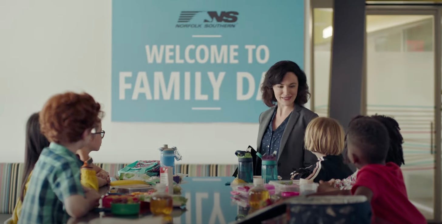 A screenshot from Norfolk Southern’s 2018 “Everyday Superheroes” ad, which features a woman speaking to a group of kids in front of a sign with Norfolk Southern’s logo.