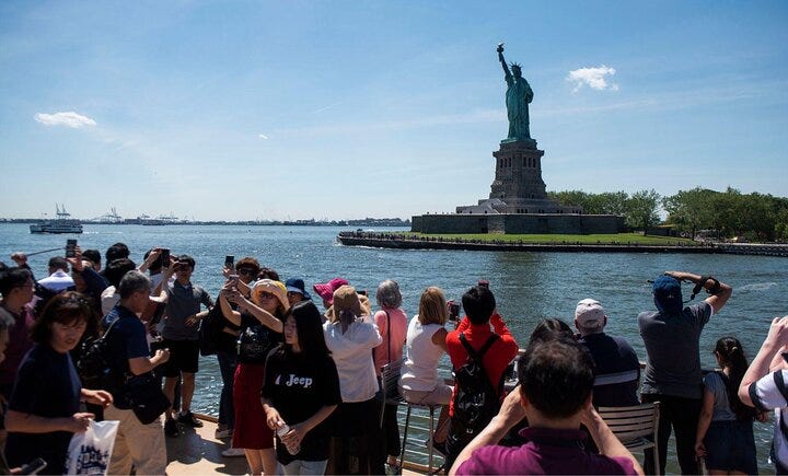 Tourists on a boat enjoy seeing the Statue of Liberty.