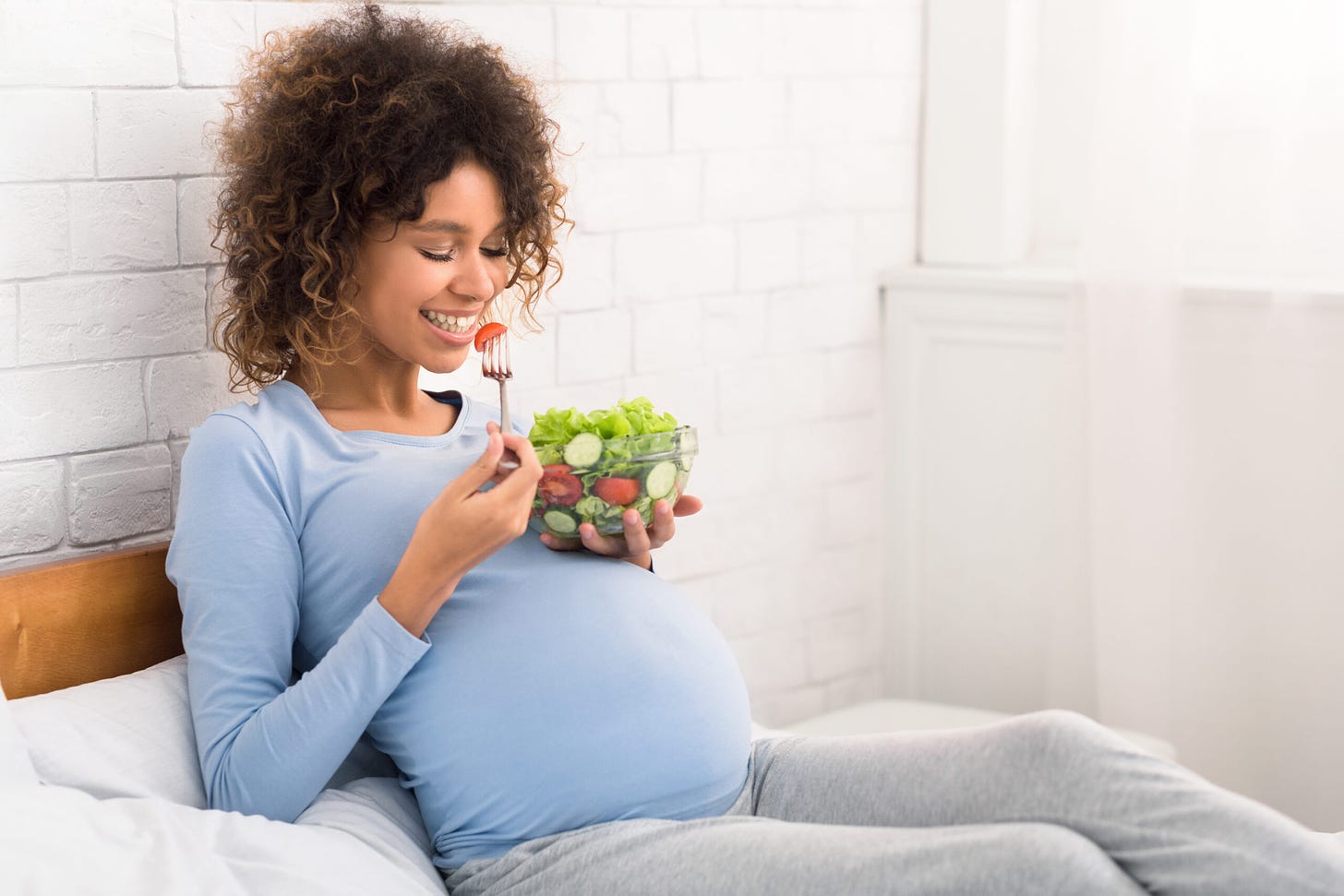 Image of a pregnant woman eating a salad and showing preferences for healthy foods