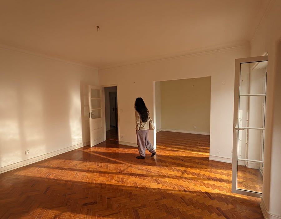 Photo of a person with long black hair walking through a sun-drenched living room.